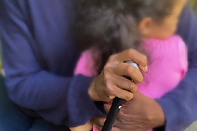 Primer plano de una abuela de etnia negra con bastón abrazando a una niña