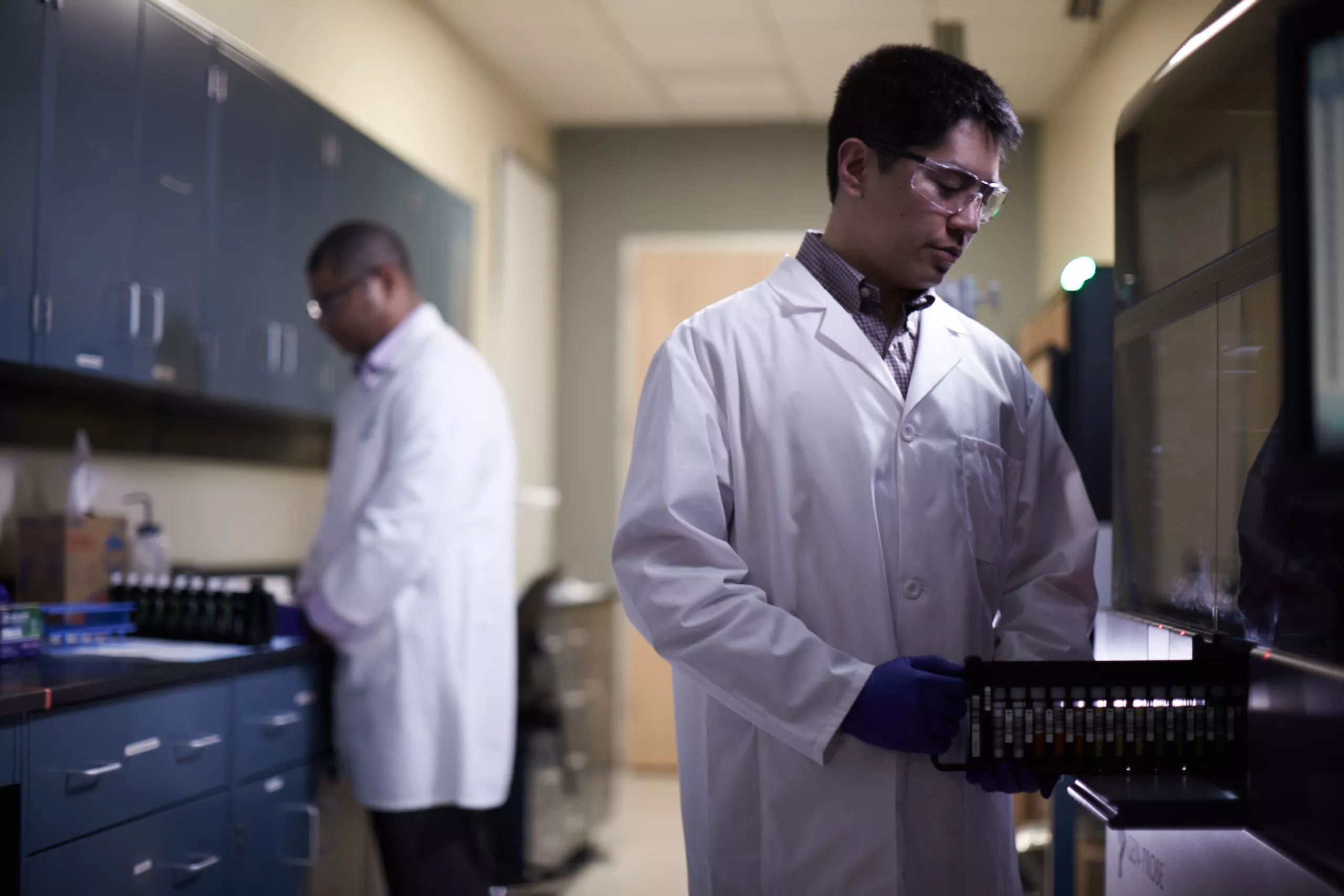 Técnico de laboratorio que introduce una bandeja de viales en un equipo médico