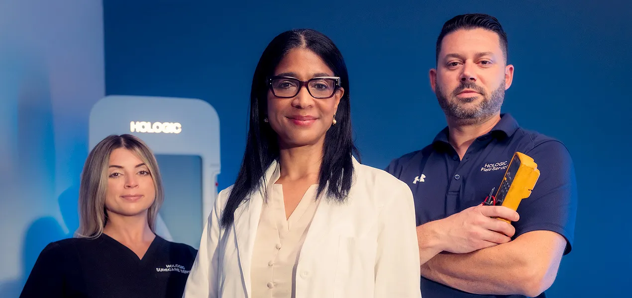 Tres profesionales sanitarios posando frente a un equipo médico de Hologic