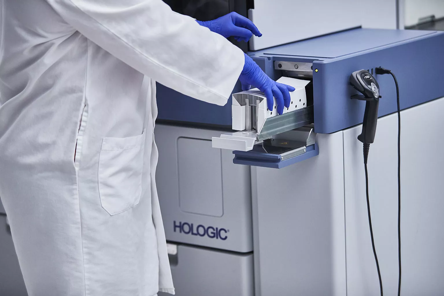 Técnico de laboratorio cargando una bandeja de tubos en un sistema Panther en un laboratorio.