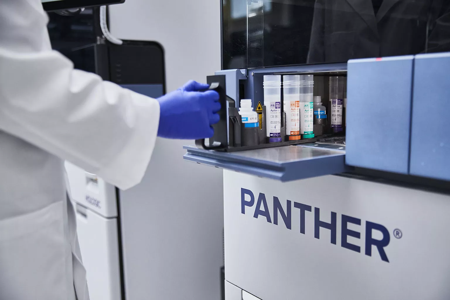 Técnico de laboratorio manipulando una bandeja de tubos en un laboratorio.