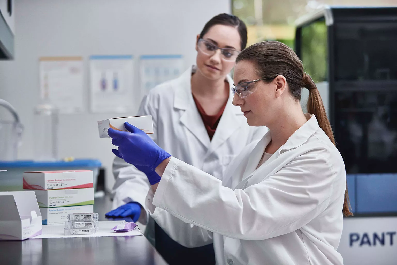 Técnicos de laboratorio sosteniendo una caja de ensayos en un laboratorio.