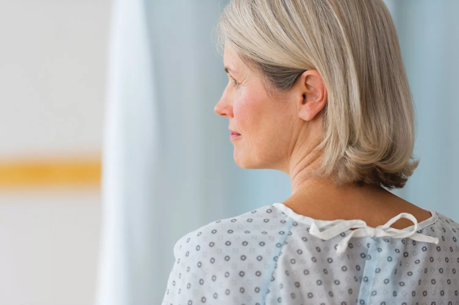Mujer de edad avanzada con ropa de hospital mirando hacia la izquierda