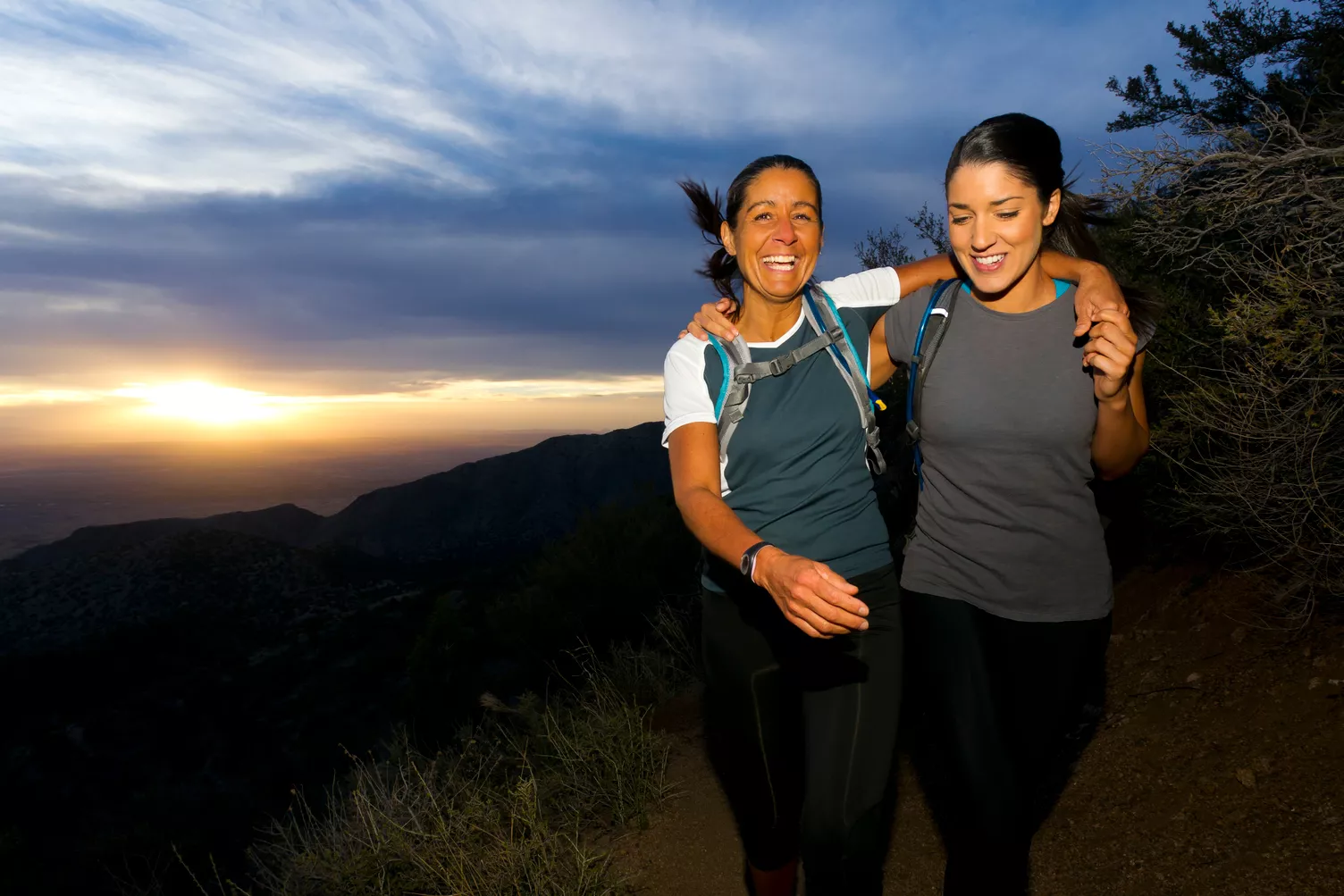 Dos mujeres subiendo por una colina al atardecer