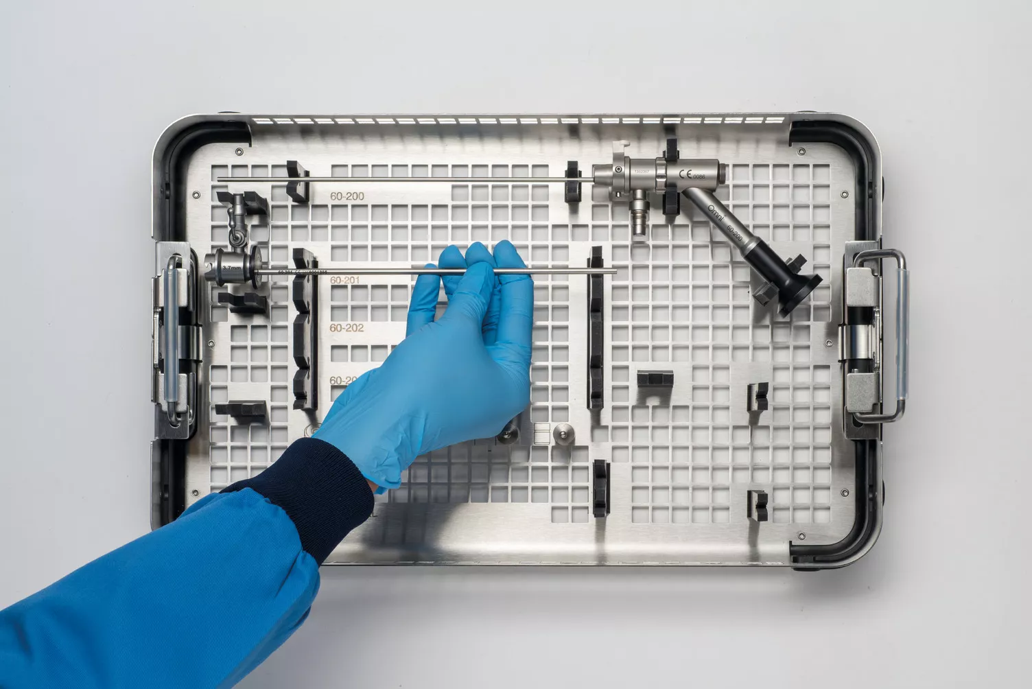Mano con guante trabajando con la bandeja médica sobre una mesa.