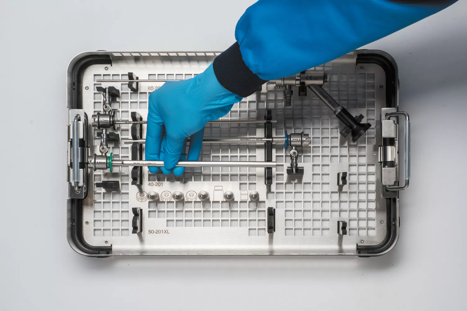 Mano con guante trabajando con la bandeja médica sobre una mesa.